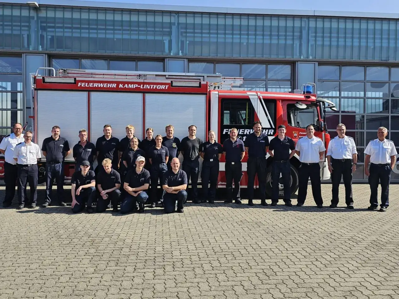 Eine Gruppe von Feuerwehrleuten steht vor einem roten Feuerwehrauto. Der Beruf des Feuerwehrmanns ist wichtig für die Sicherheit.