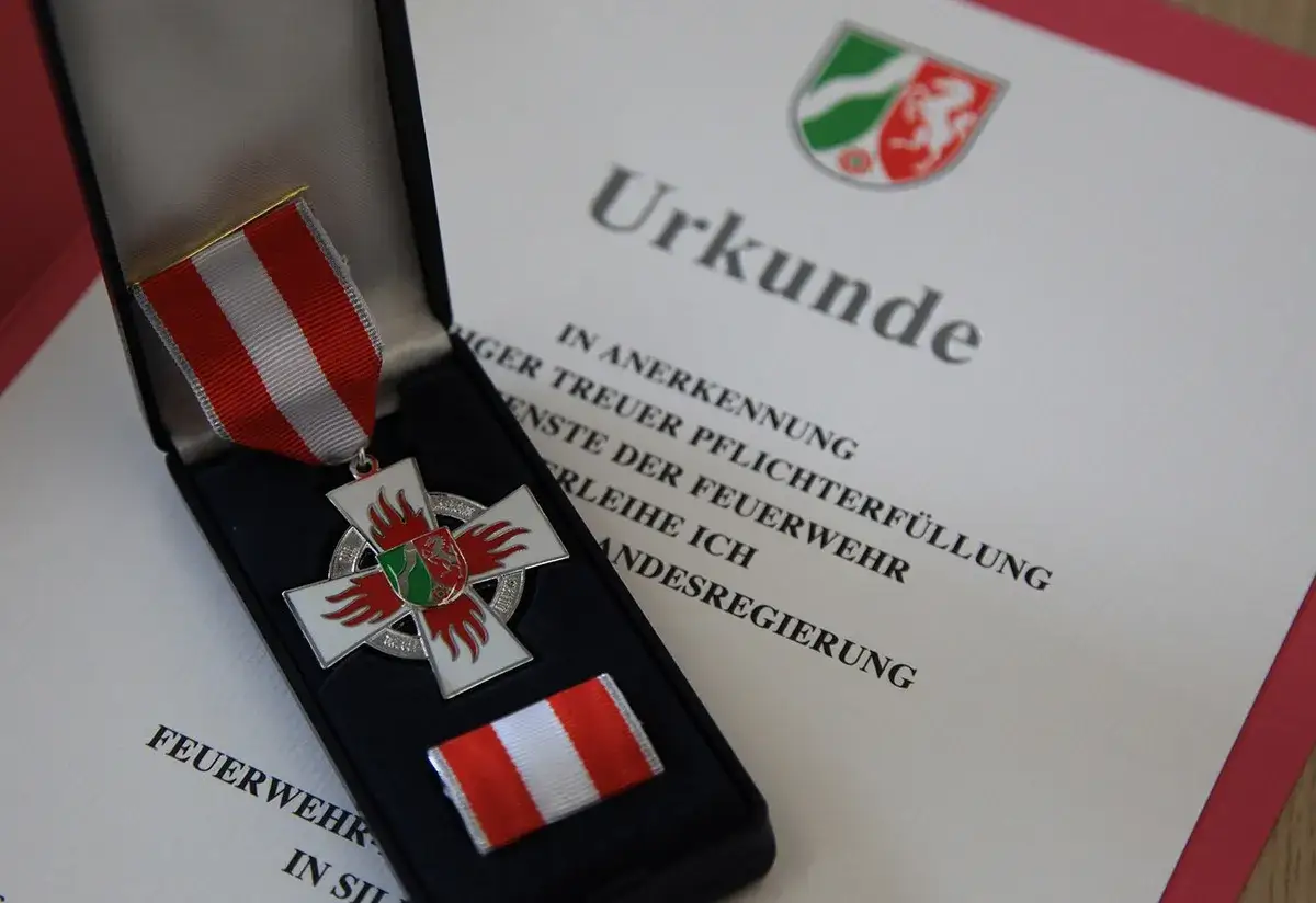 Feuerwehr Ehrenzeichen in einer Schatulle, daneben eine Urkunde für treue Pflichterfüllung bei der Feuerwehr.