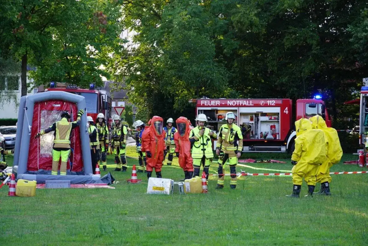 Feuerwehr-Veranstaltungen: Einsatzkräfte in Schutzanzügen üben den Umgang mit Dekontaminationsduschen und Löschfahrzeugen.