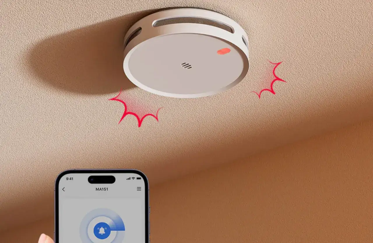 Rauchmelder an der Decke mit roter Warnanzeige, verbunden mit einer Rauchmelder App auf dem Smartphone.