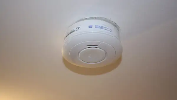 Ein weißer Rauchmelder hängt an der Decke. Er scheint von alleine auszugehen, da kein Alarm zu hören ist.